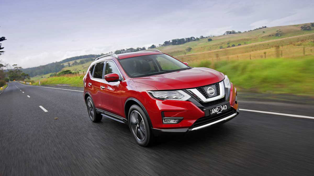 Front side view of a red Nissan X-Trail 2017 car in motion on a country road