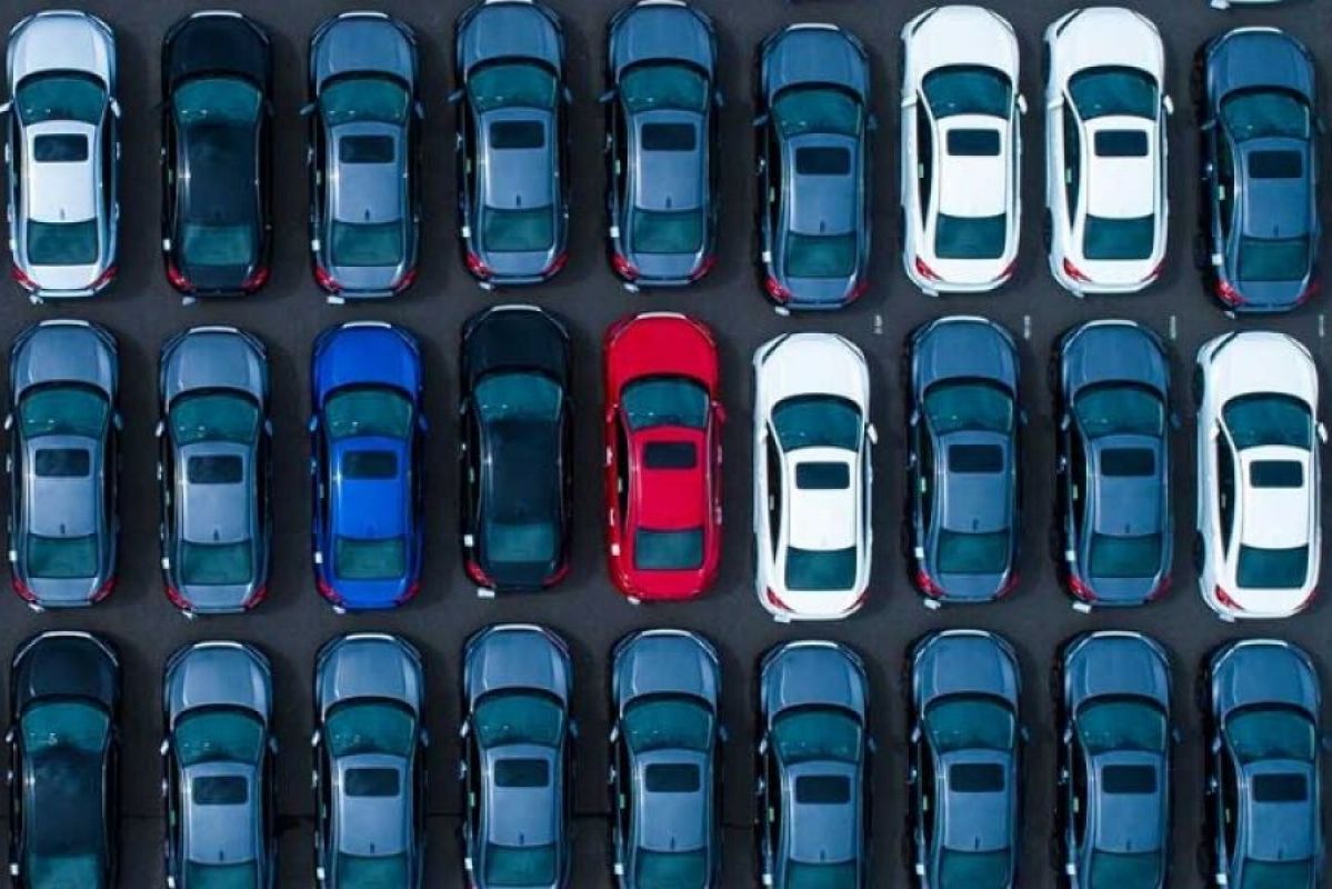 rows of blue cars with a red car in the centre