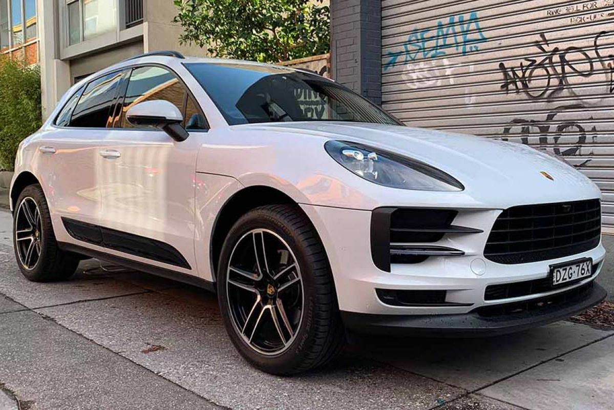 White Porsche Macan parked infront of garage door