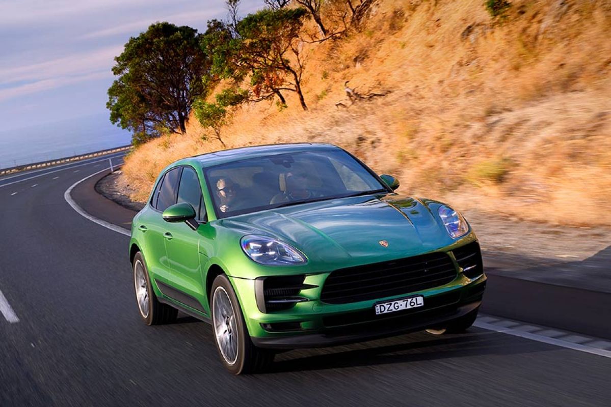 Front of a green Porsche Macan S driving on a coastal road