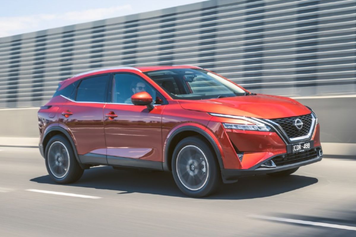 A red Nissan Qashqai driving along a highway
