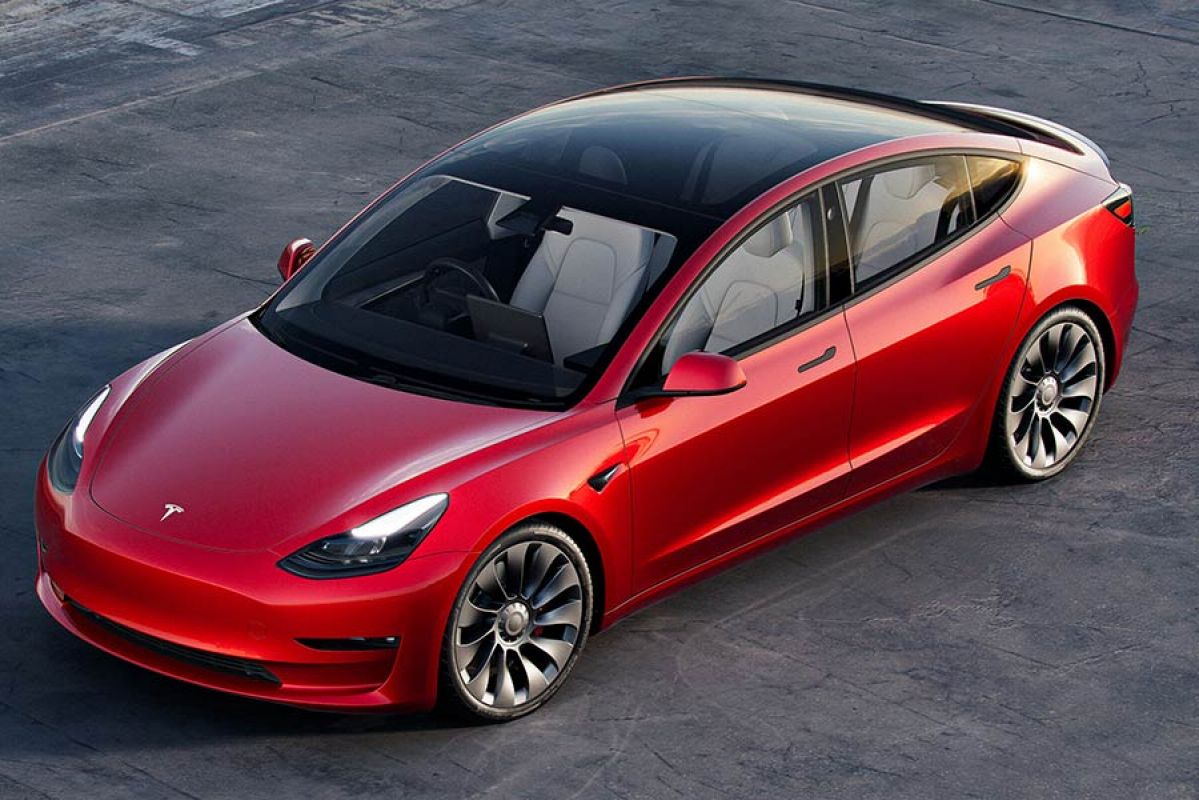 A red and black Tesla Model 3 in a parking lot