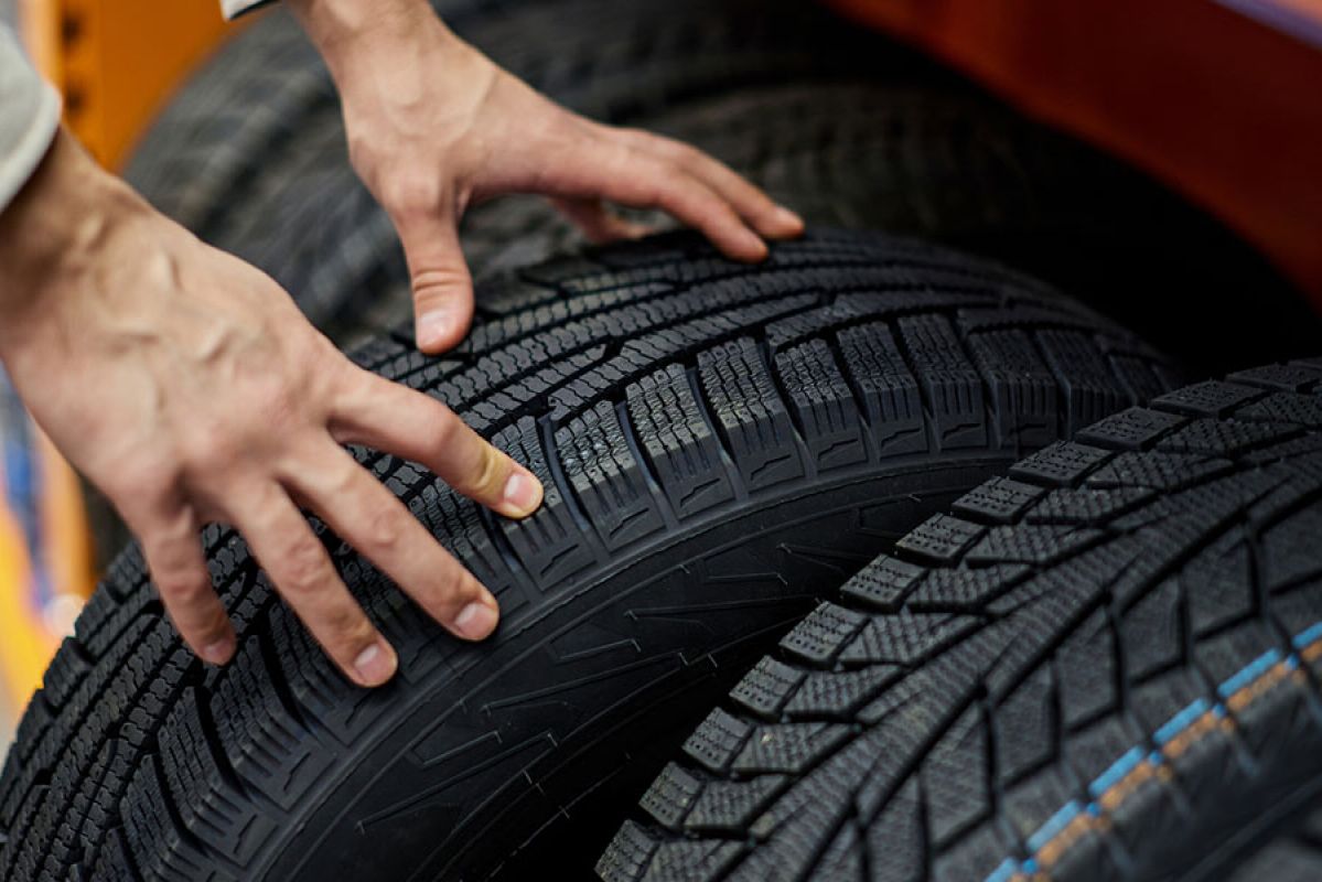 Hands inspecting a car tyre
