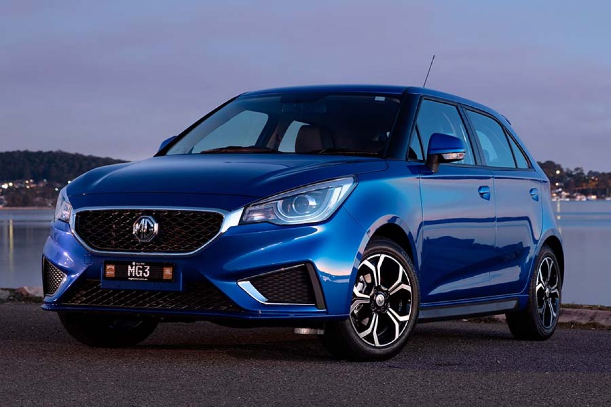 close up image of blue MG3 Core parked in front of lake at dusk