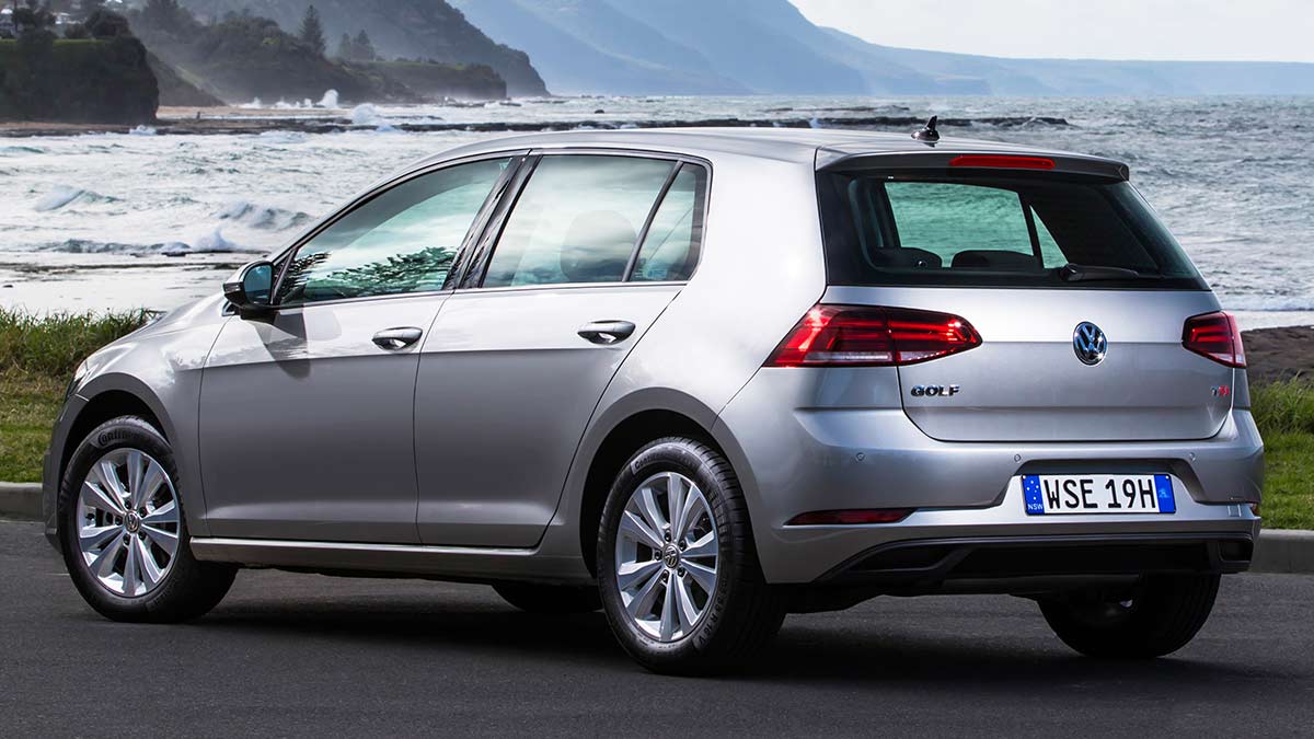 Rear side view of a silver Volkswagen Golf 7.5 2017 car parked on a road next to the sea