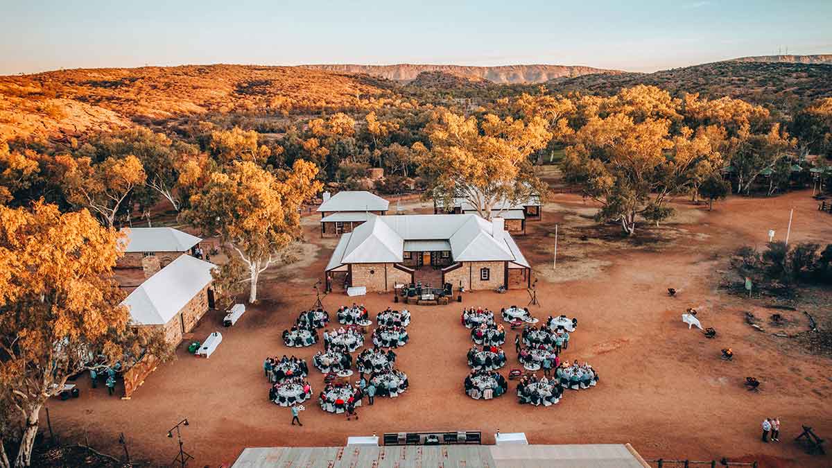 Tables of diners set up around a homestead. 