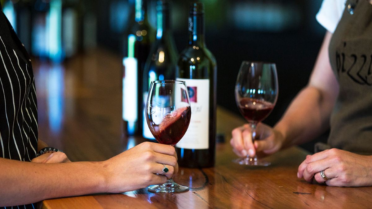 People swirling glasses of wine at a table