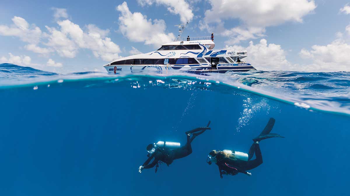 Deep sea diving in clear blue water right under a boat