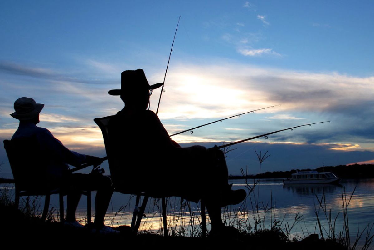 Two people fishing at night