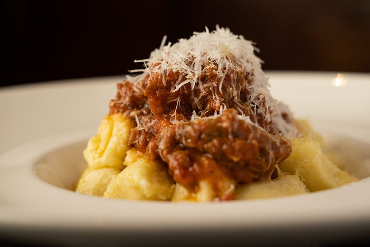 Flat-lay display of a bowl of freshly made gnocchi and its ingredients on the table