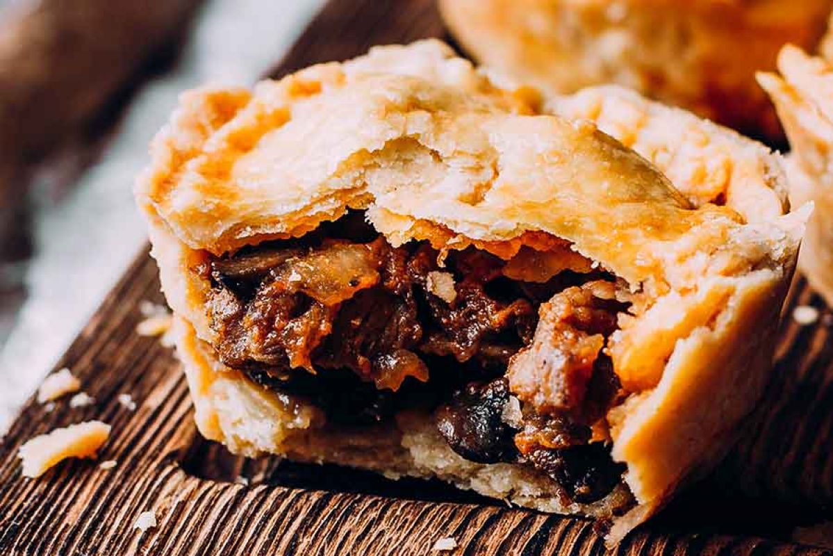 beef pie cut in half on a chopping board