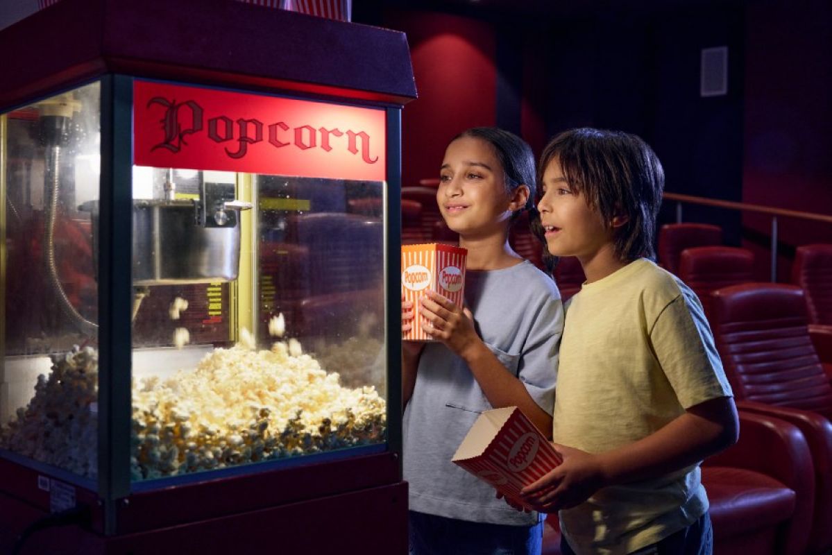 two children getting popcorn in a small cinema