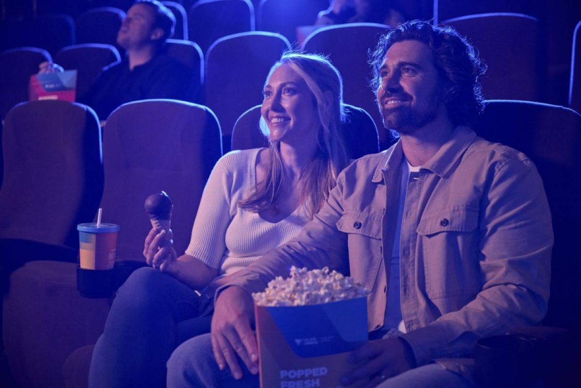 A man and woman enjoying a film in a darkened theatre with choc tops and popcorn