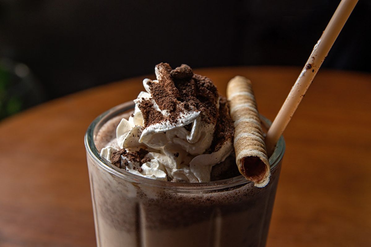 Chocolate drink in a glass with cream and wafer on top.
