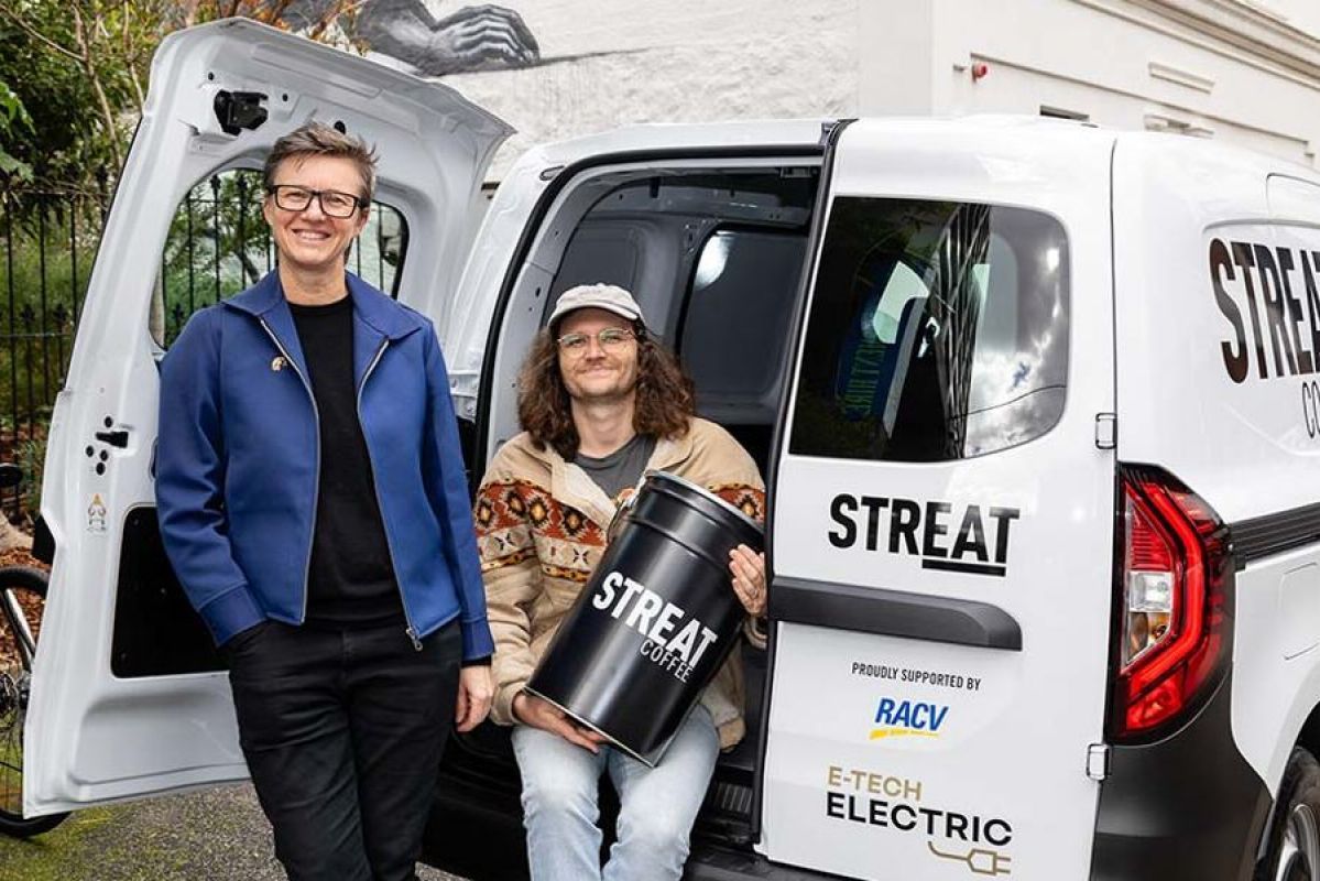 Two people from street smiling from the back of a new electric van for social enterprise cafe STREAT