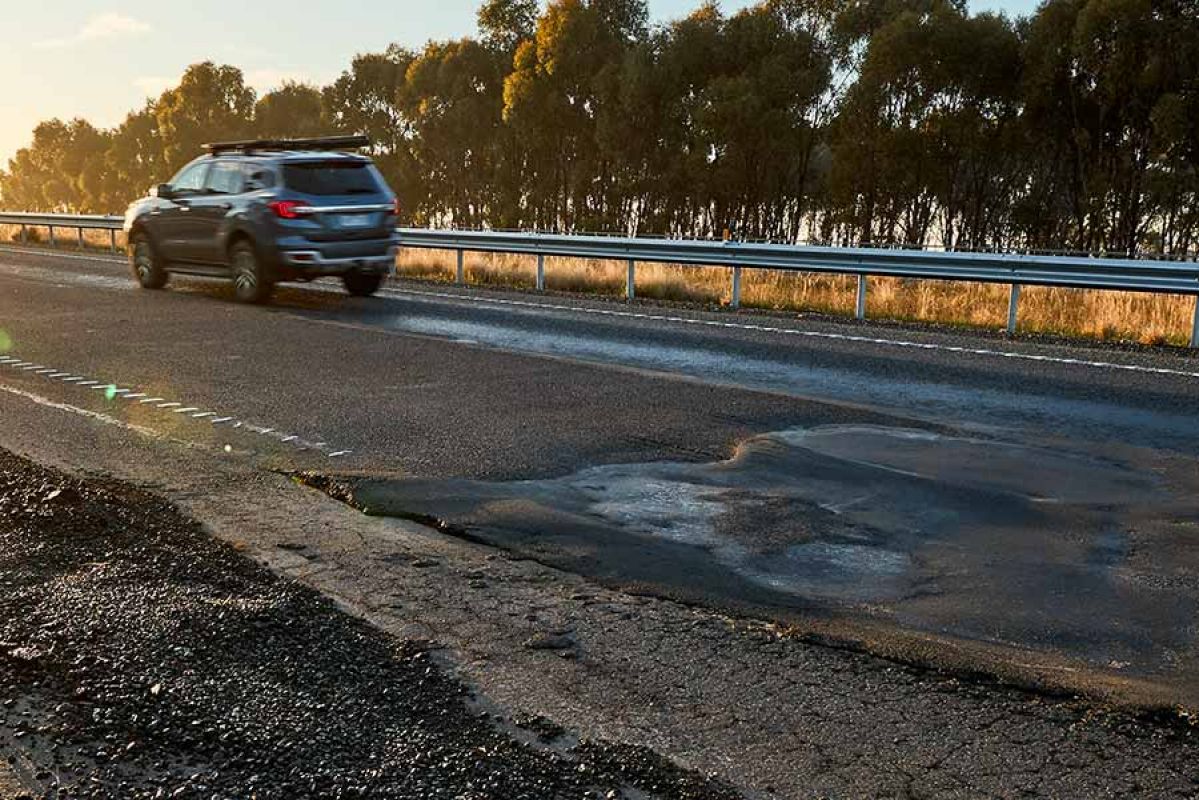 Car travelling on road with uneven surface