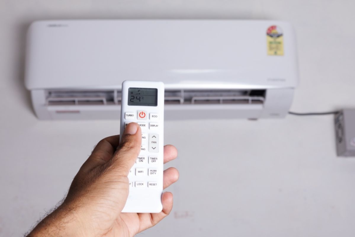 man turning on an air conditioner with its remote control