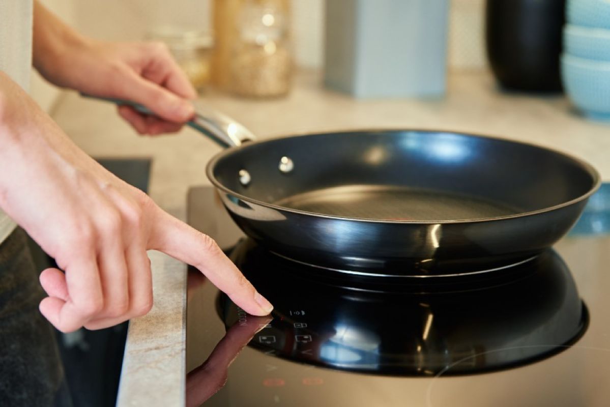 A person turning on an induction cooktop