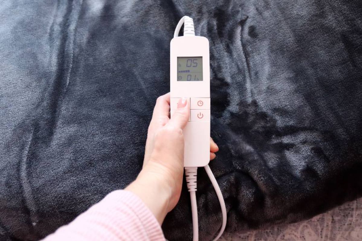 woman adjusting temperature of gray electric blanket