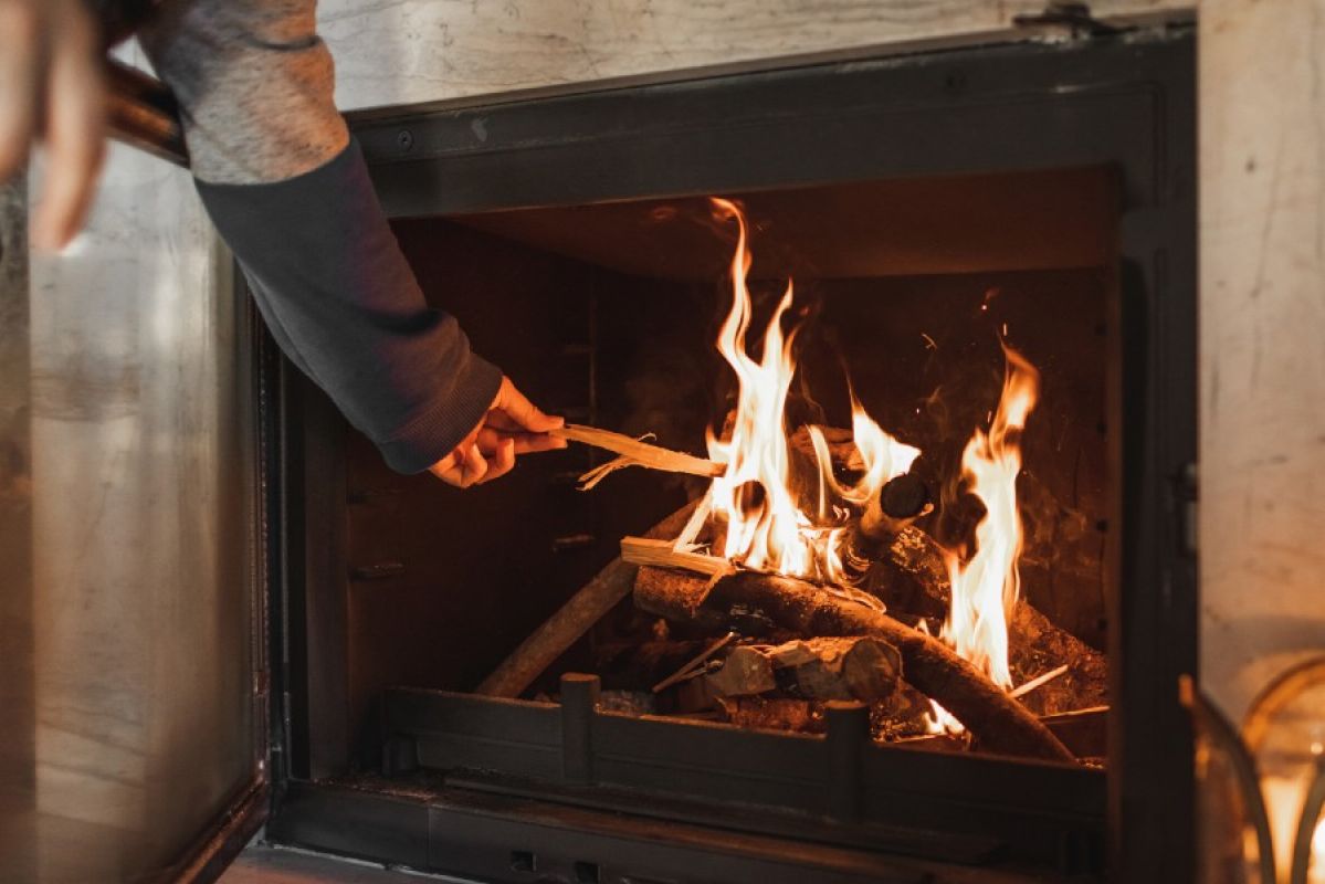person placing a stick on an indoor fireplace