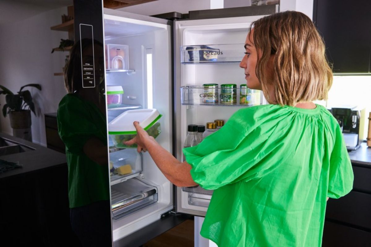 woman putting container in fridge