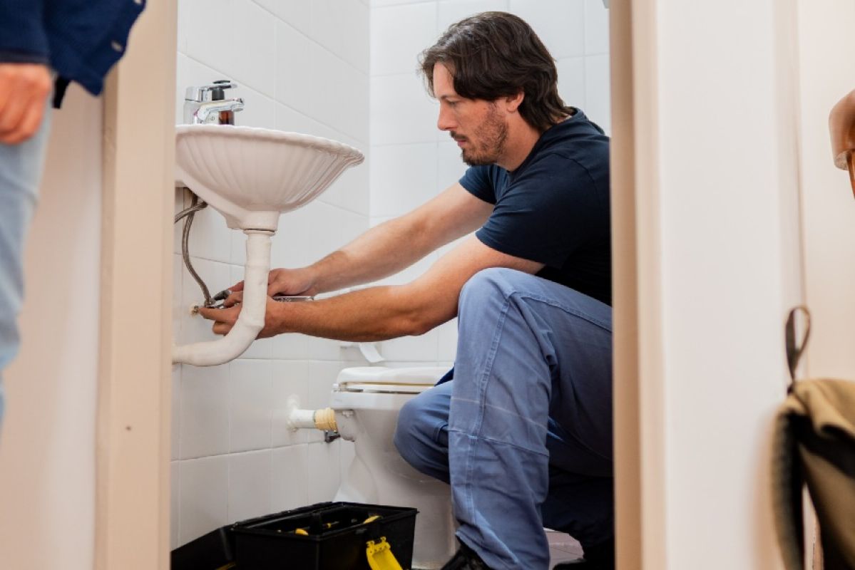 man fixing a sink flexi-hose while woman watches