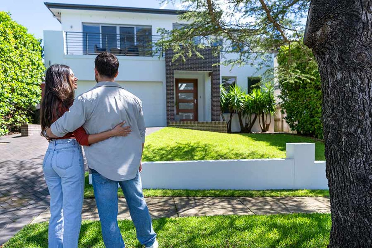 Young couple arm-in-arm outside new home