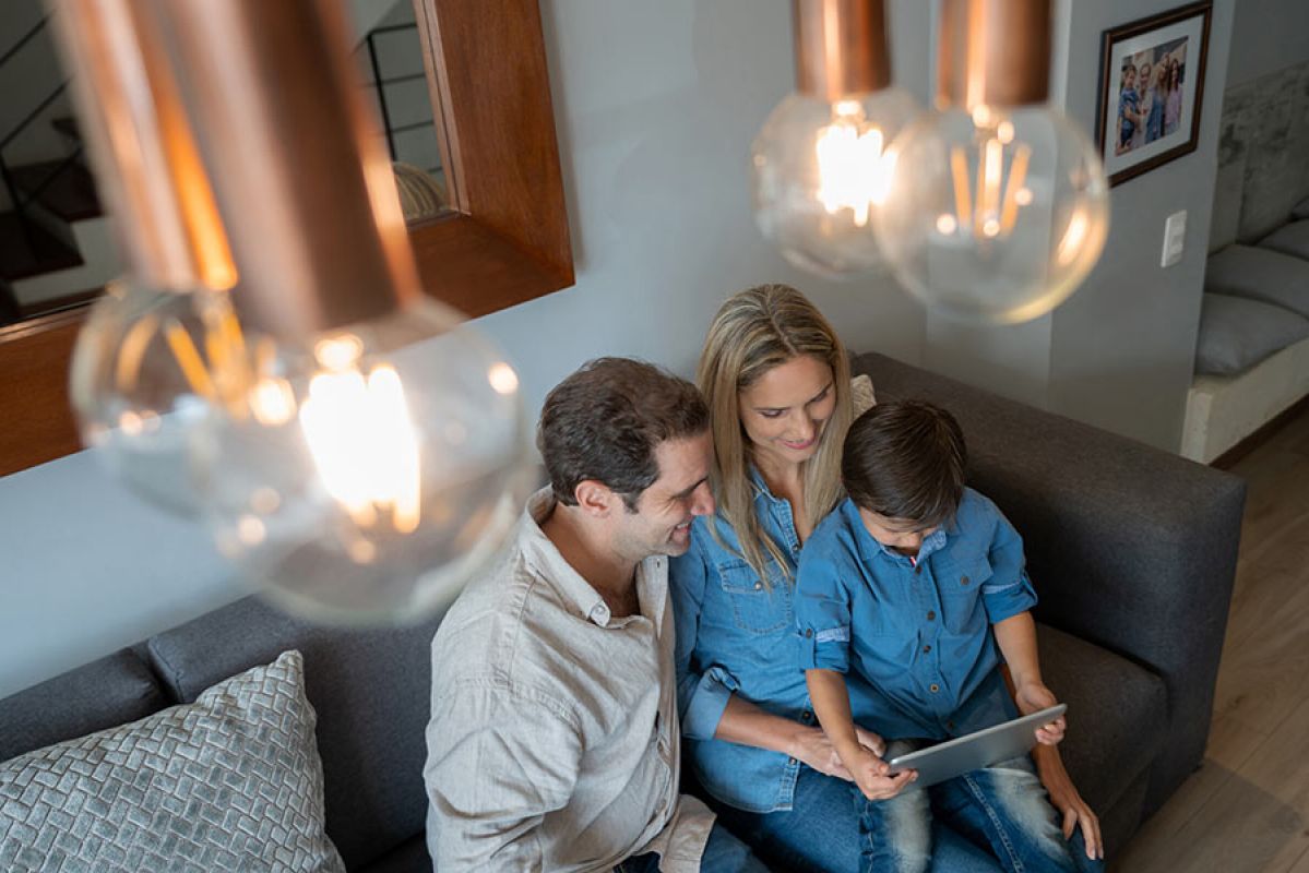 Overhead shot of family on couch looking at tablet with lights in foreground.