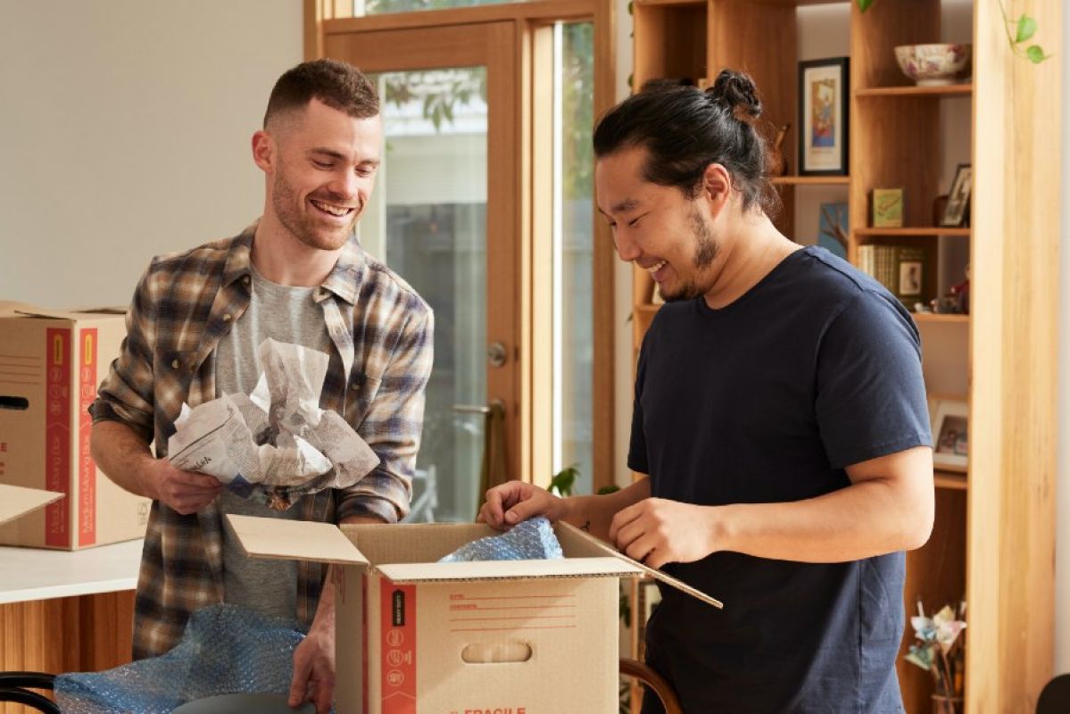 two young men unpacking in a new home