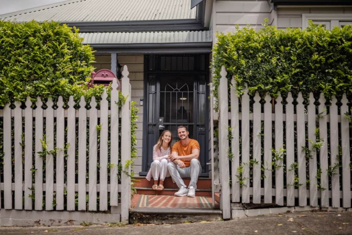 young couple sitting outside their home