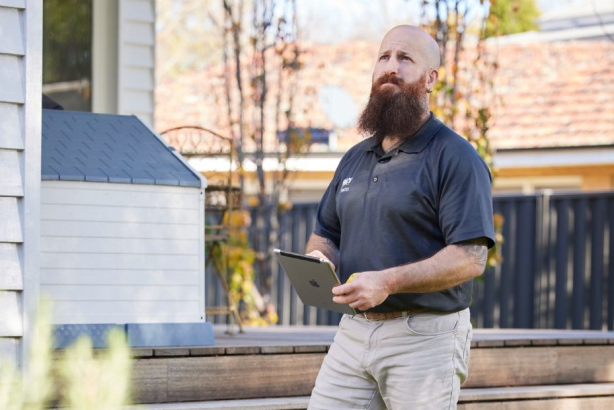 RACV property inspector typing on tablet outside a home