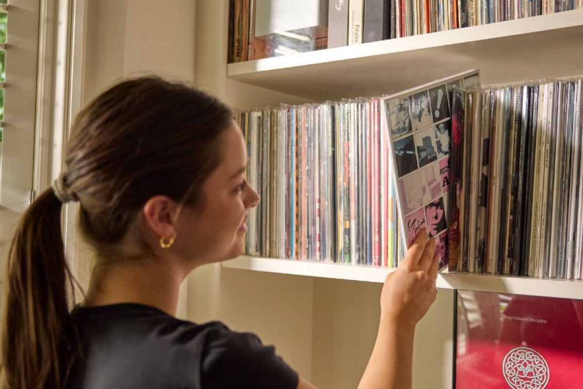 A young woman pulls a record from a collection