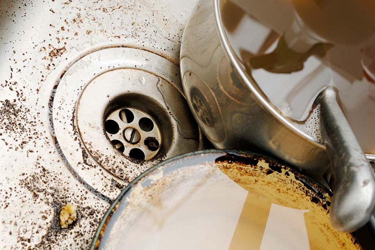 person rinsing food scraps in their kitchen sink