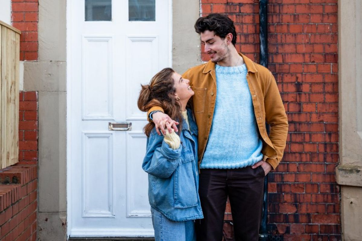two young people outside their home