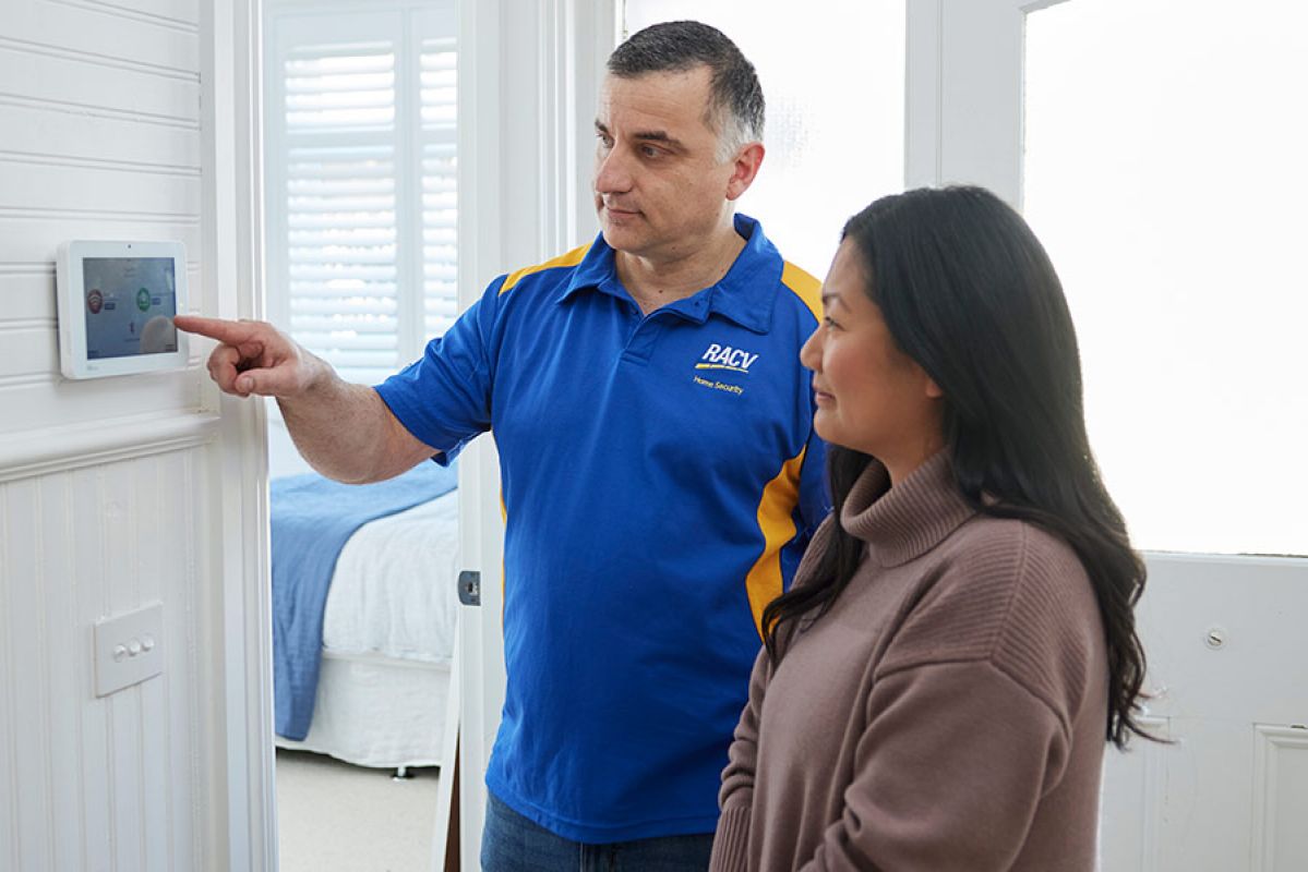 RACV security technician showing female customer the alarm panel in home