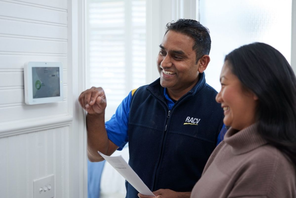 An RACV home security technician shows a woman how to use her new home security control panel