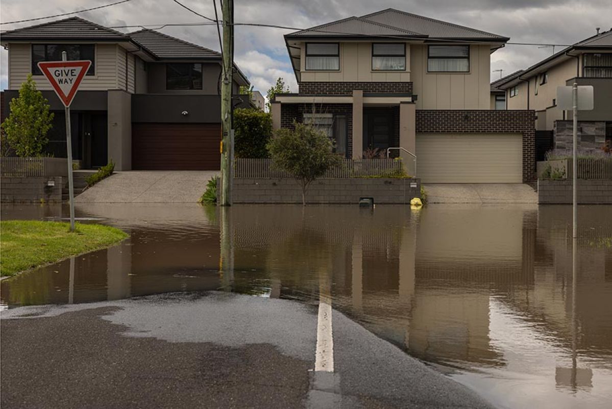 Flood water across road in front of three double-storey houses in Maribyrnong