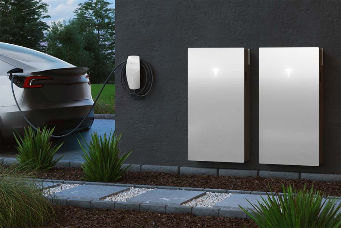 EV in driveway attached to charger and two solar batteries