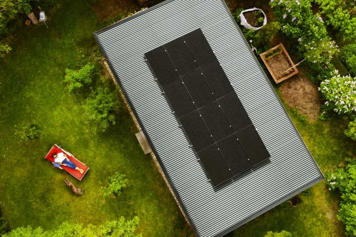 aerial view of rooftop solar panels with woman and dog lying in backyard