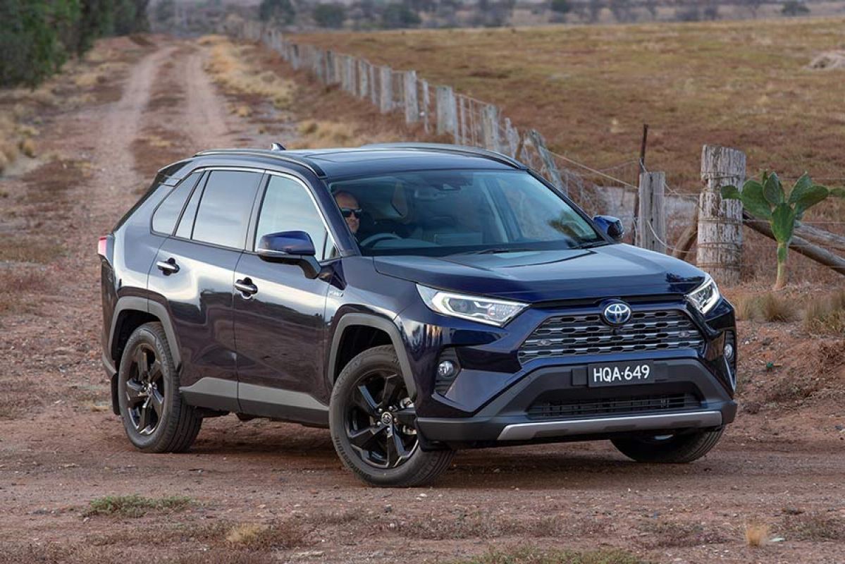 Black Toyota RAV4 Hybrid turning left at dirt road intersection in rural area