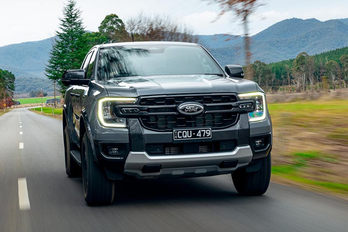 Metallic grey Ford Ranger Tremor dual-cab ute on rural tree-lined bitumen road with high country behind