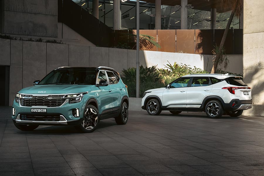 Green and white Kia Seltos small SUVs parked in front of office building