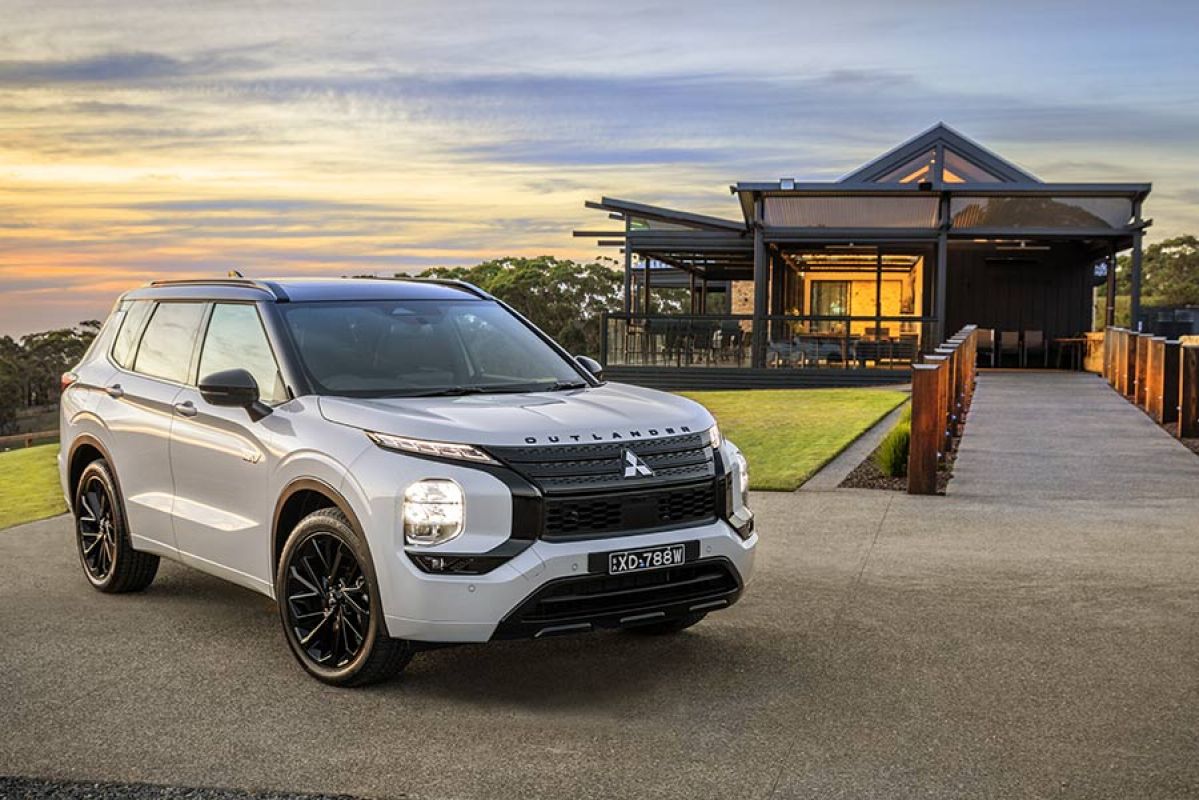 White Mitsubishi Outlander GSR PHEV parked in front of building at sunset in rural location