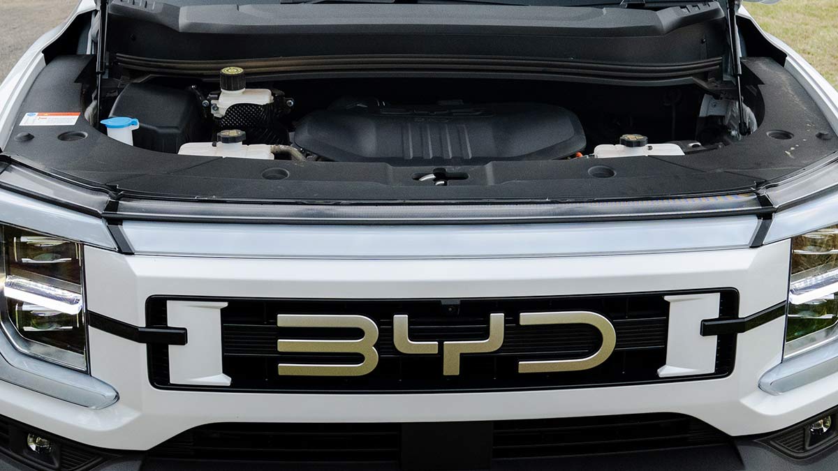Front-end view of white BYD Shark 6 ute with bonnet up showing engine bay