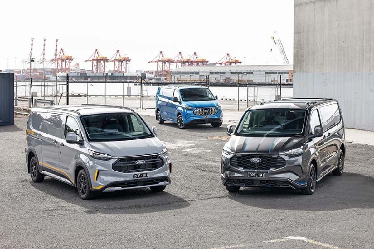 Grey, silver and blue Ford Transit Custom Trail, EV and PHEV vans on dock in front of container terminal and gantry cranes.