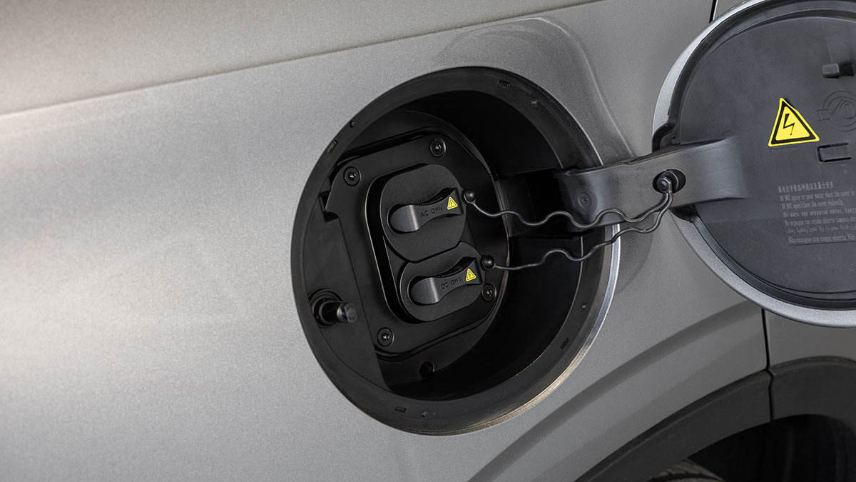AC and DC charging ports behind flap on body of GWM Haval H6 plug-in hybrid SUV.