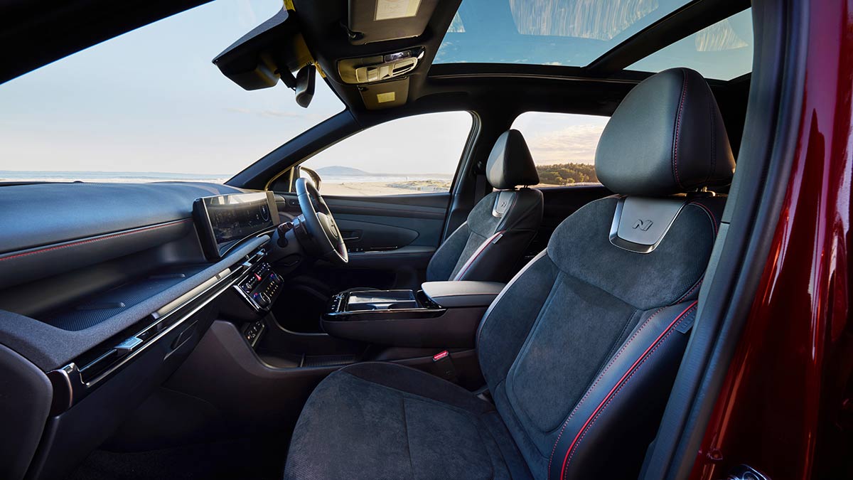 Front passenger area inside red Hyundai Tucson Premium N Line Hybrid SUV parked at beach
