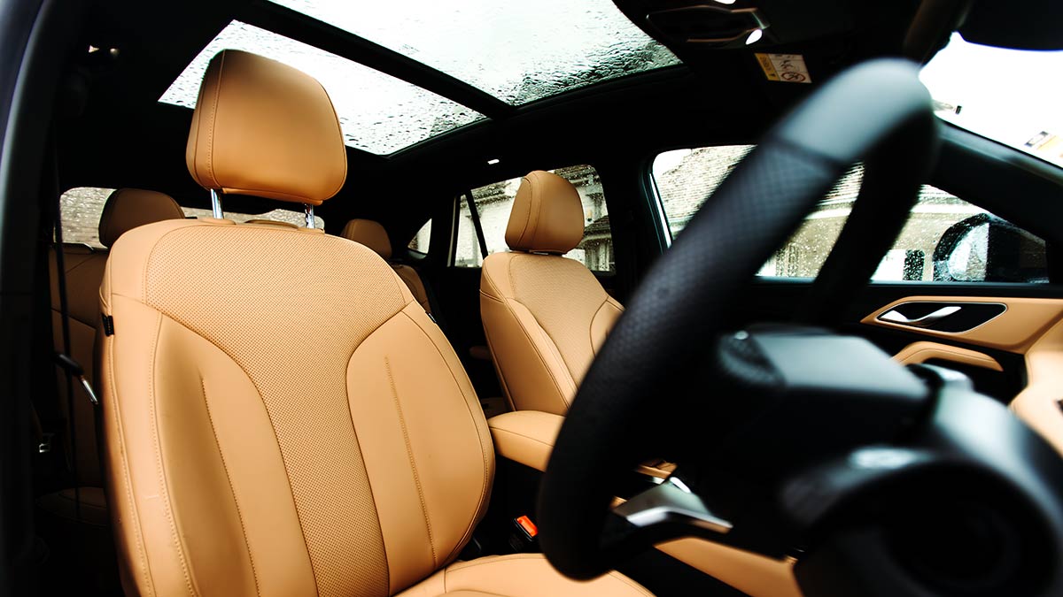 Interior view from driver's door of MG HS Essence with tan seats and panoramic sunroof