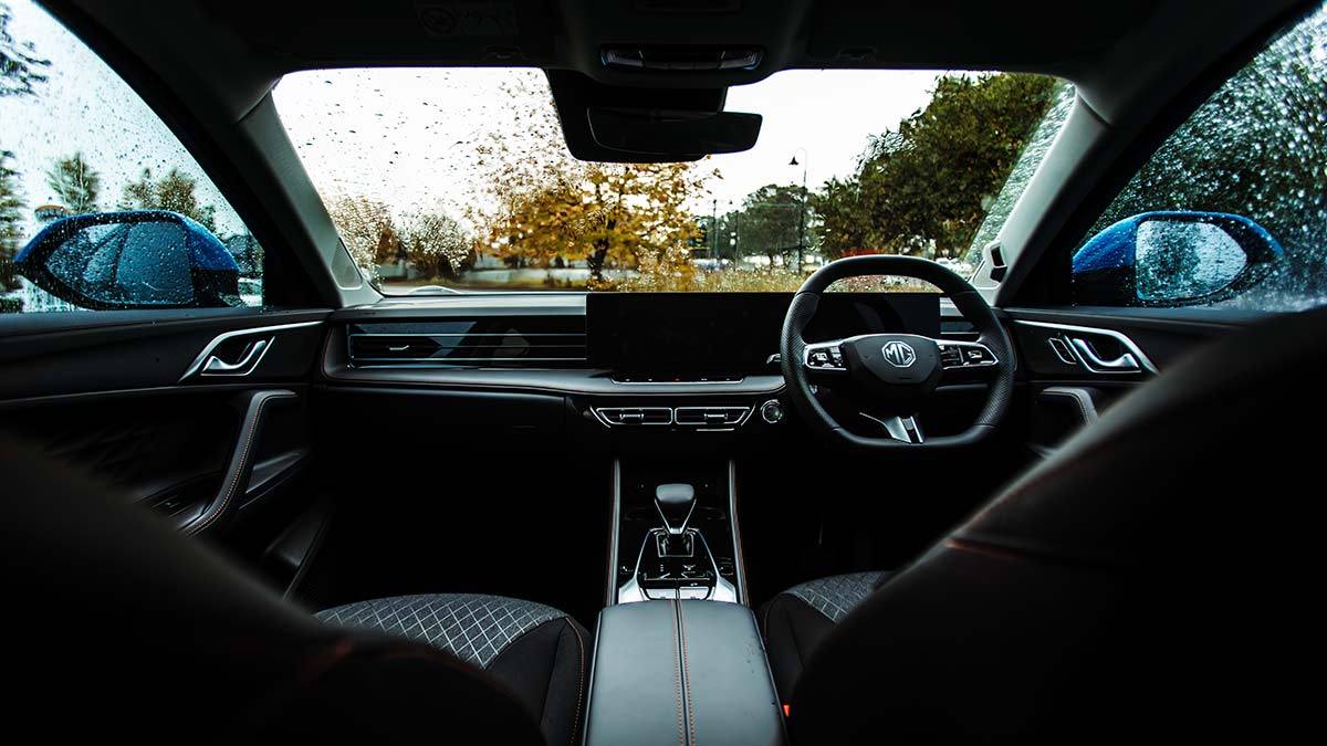 Dashboard of MG HS SUV with dual screens and view out windscreen of yellow autumn leaves