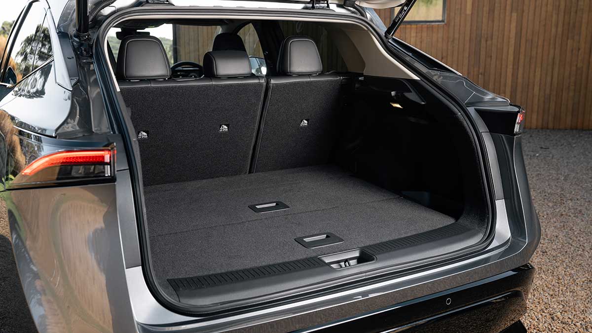 Boot area inside grey Nissan Ariya electric SUV parked in driveway of country home.